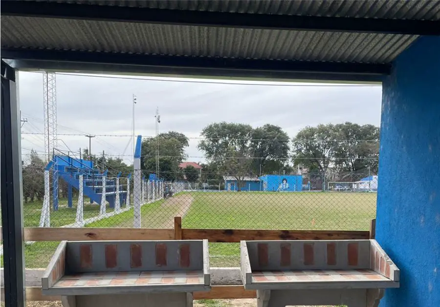 Asadores de ladrillo bajo techo, con vista al predio del club